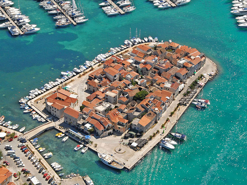 Tribunj je malo, slikovito in očarljivo ribiško naselje, oddaljeno približno deset kilometrov od Šibenika. Njegove krasne ozke ulice spominjajo na bližnja, turistično bolj izpostavljena obalna mesta. A ravno ta relativna neodkritost, mir celo na višku sezone, predstavlja njegovo glavno privlačnost.